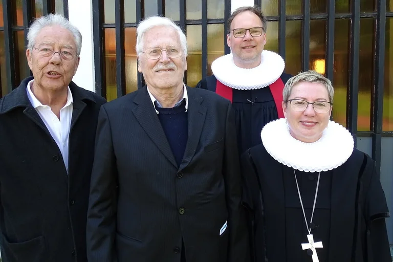 Vier Personen stehen vor einer Kirche. 