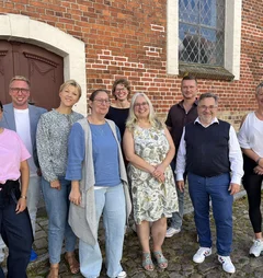 Neun Frauen und Männer stehen für ein Gruppenbild zusammen