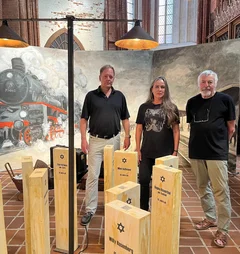 Drei Menschen stehen vor einem Gemälde und hinter einer Kunstinstallation