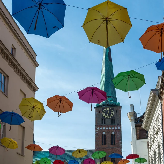 Aufgespannte Regenschirme in verschiedenen Farben, an mehreren Seilen aufgehängt - Im Hintergrund St. Jakobi Lübeck