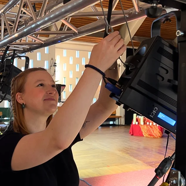 Eine junge Frau arbeitet an einem großen Scheinwerfer.