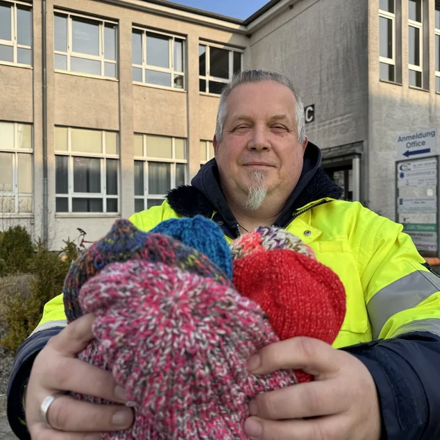Ein Mann hält Mützen in der Hand 