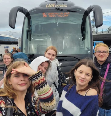 Eine Gruppe junger Menschen macht ein Selfie vor einem Reisebus