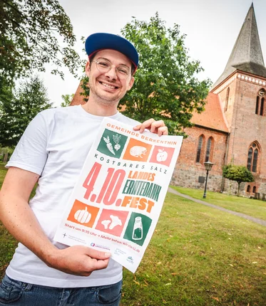 Ein Mann steht mit einem Plakat vor einer Kirche 