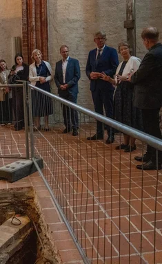 Menschen stehen an einer Grabungsstelle in einer Kirche
