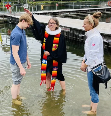 Pastorin Nicola Nehmzow tauft Ben Joel Hinz. Mit dabei: Mutter Kati Hinz. Sie stehen alle im Wasser, die Pastorin hält eine Hand über den Kopf des jungen Mannes.