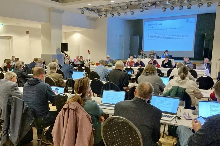 Menschen sitzen in einem Raum, in dem eine Veranstaltung stattfindet. 