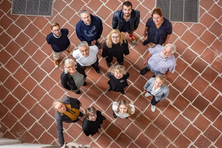 Menschen stehen in einem Raum und blicken nach oben. 