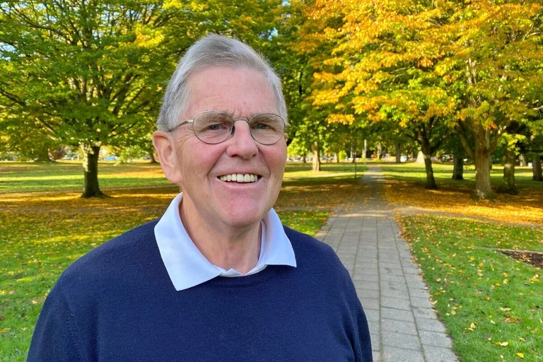 Ein Mann steht in einem herbstlichen Park