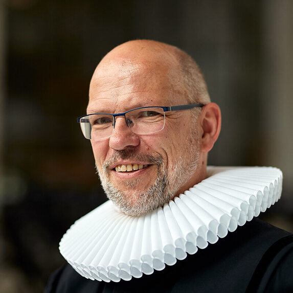 Mann mit Halskrause lächelt in die Kamera
